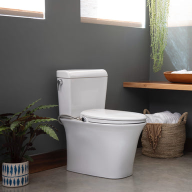 White toilet  with Brondell Swash Ecoseat Non-Electric Bidet Seat installed in a bathroom with a dark gray wall, wooden shelf, and plants.