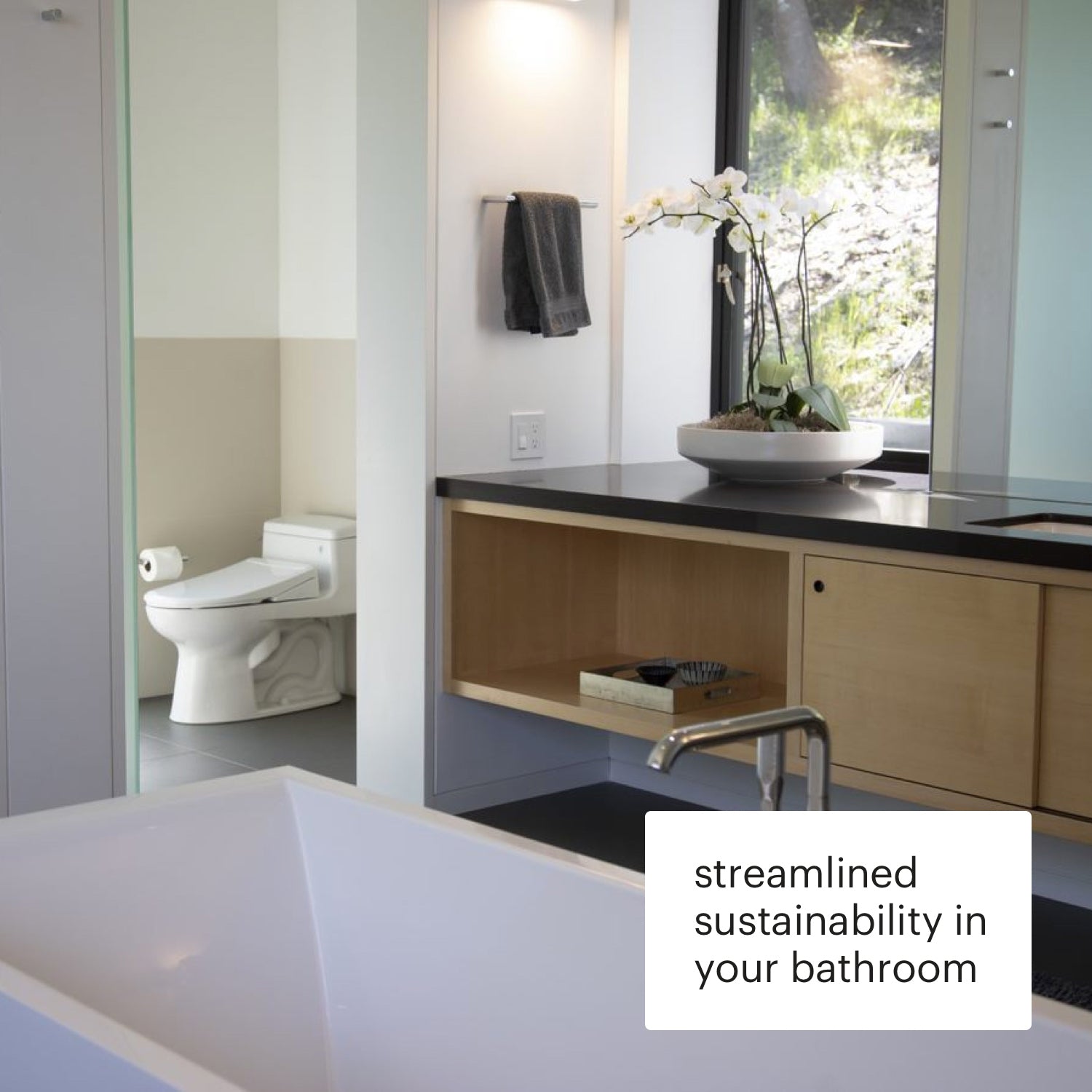 Modern bathroom with a sink, mirror, and window, featuring text 'streamlined sustainability in your bathroom'. Brondell Swash Thinline T22 electric bidet shown installed in toilet room.